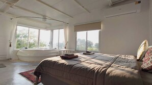 A spacious bedroom with a large bed, a bathtub, and a view of the outdoors. - Khao Chi Chan Resort (Sattahip)