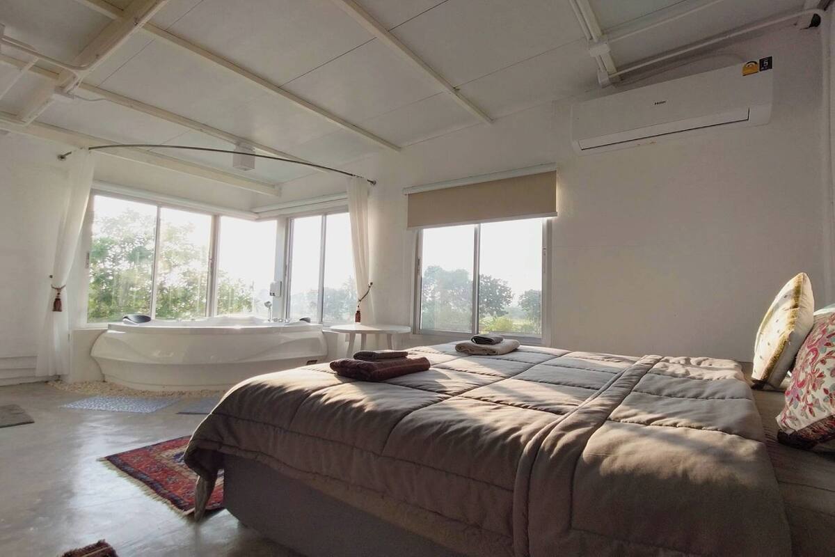 Um quarto espaçoso com uma cama grande, uma banheira e vista para o exterior.