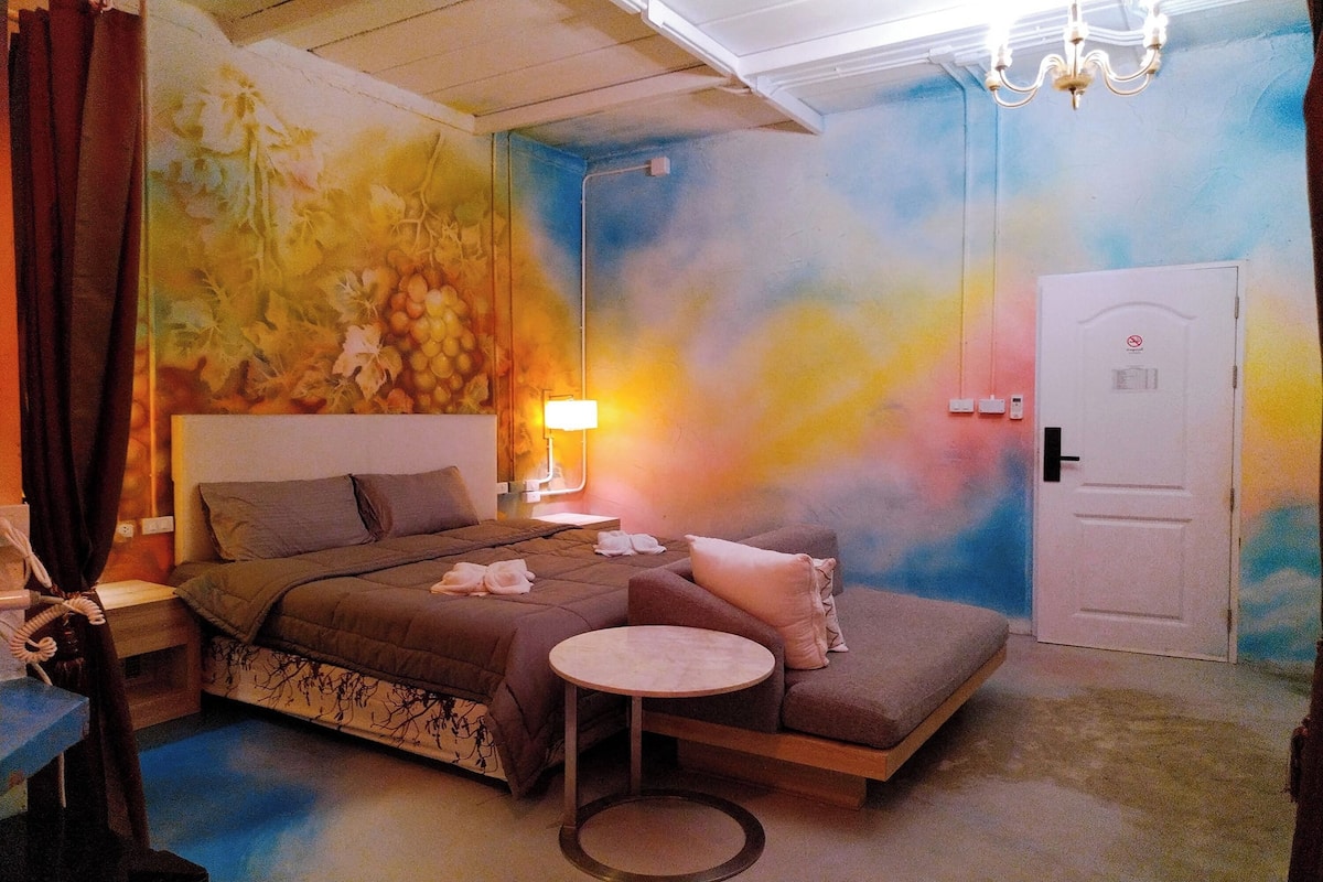 Quarto com cama, mesa de cabeceira e mesa redonda.