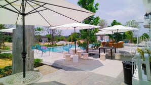 A poolside area with outdoor seating, umbrellas, and a pool. - Khao Chi Chan Resort (Sattahip)