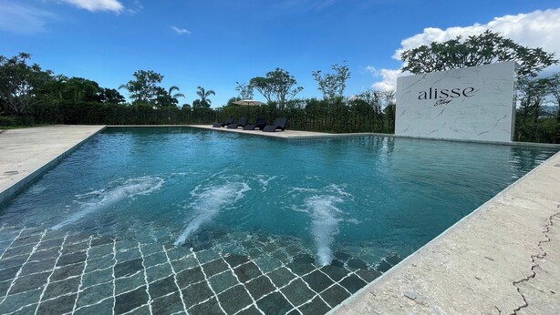 Una piscina con un letrero que dice "alisse Stay" y una zona de terraza con mosaicos.