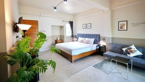 Un dormitorio moderno con una cama, mesitas de noche, un sofá y una planta en maceta.