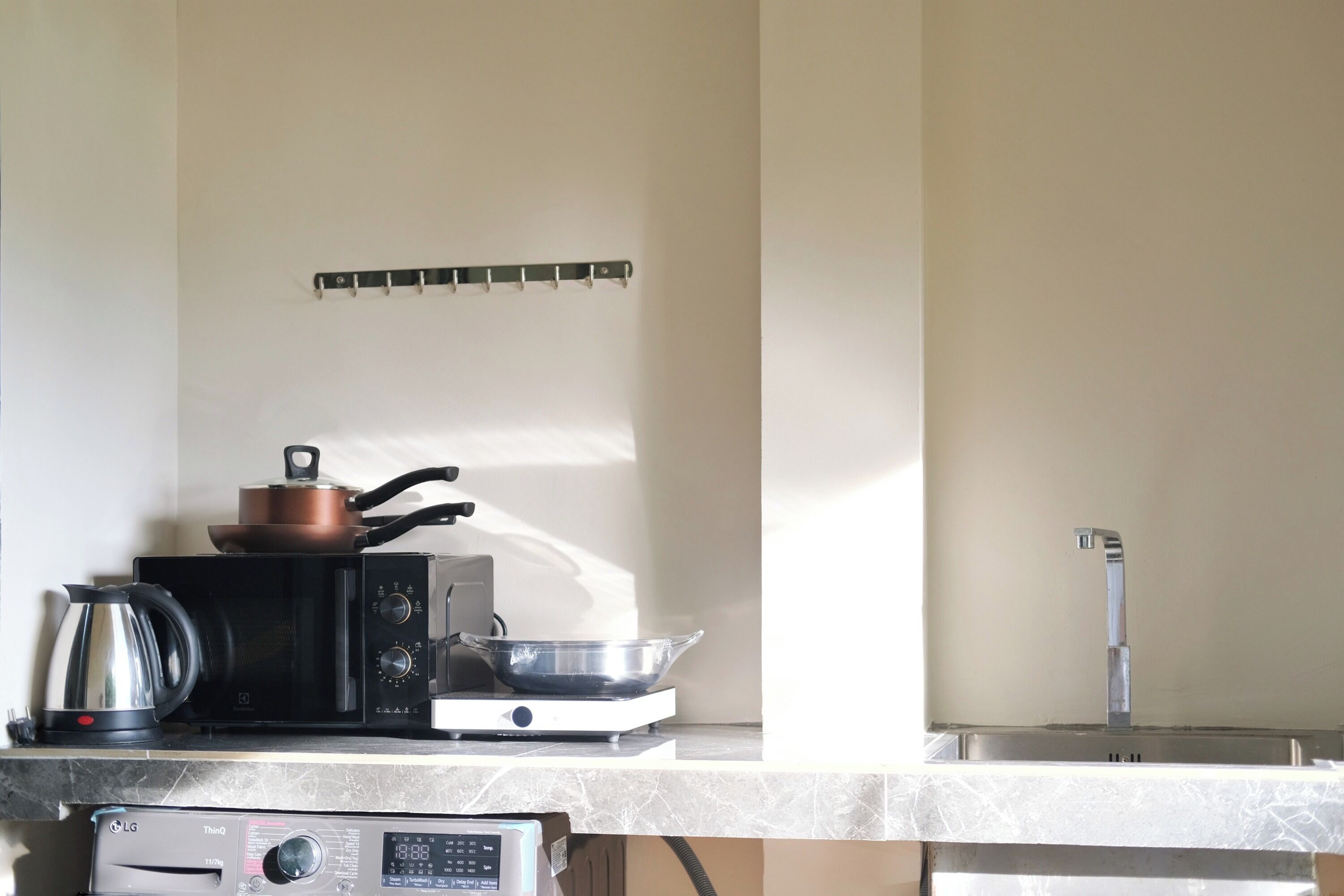 A kitchen with a microwave, kettle, and a pot on the counter.