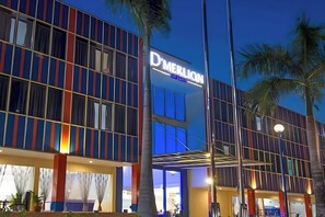 A modern hotel with a prominent 'D'MERLION' sign, featuring a multi-story structure with large windows and a covered entrance area. - D'Merlion Hotel (Batam)
