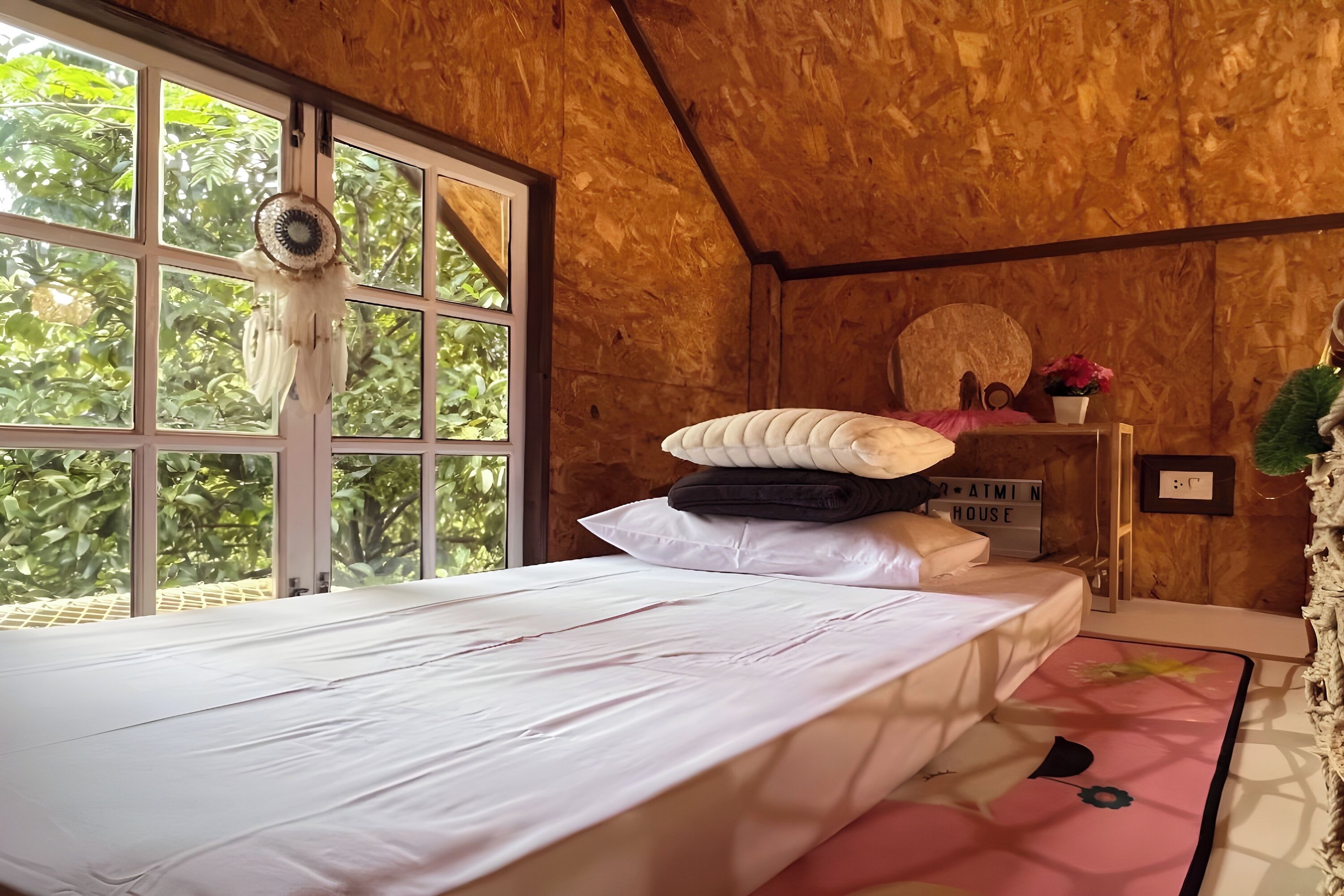 A wooden room with a bed, a window, and a shelf with a sign.