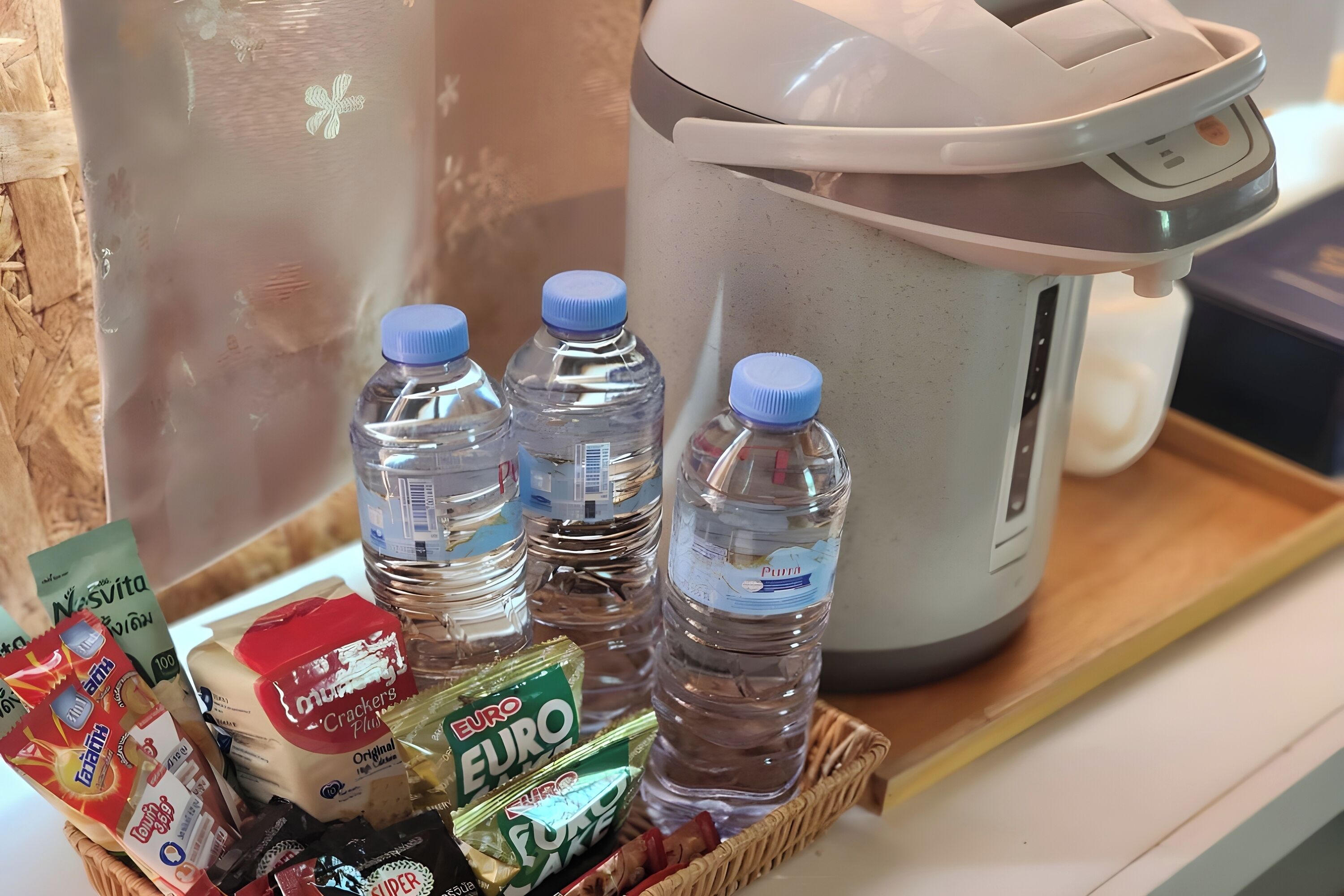 A kitchen area with a rice cooker, water bottles, and various food items including snacks and a milk carton.