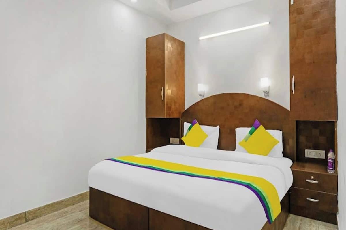 A hotel room with a bed, wooden headboard, bedside tables, and a nightstand.