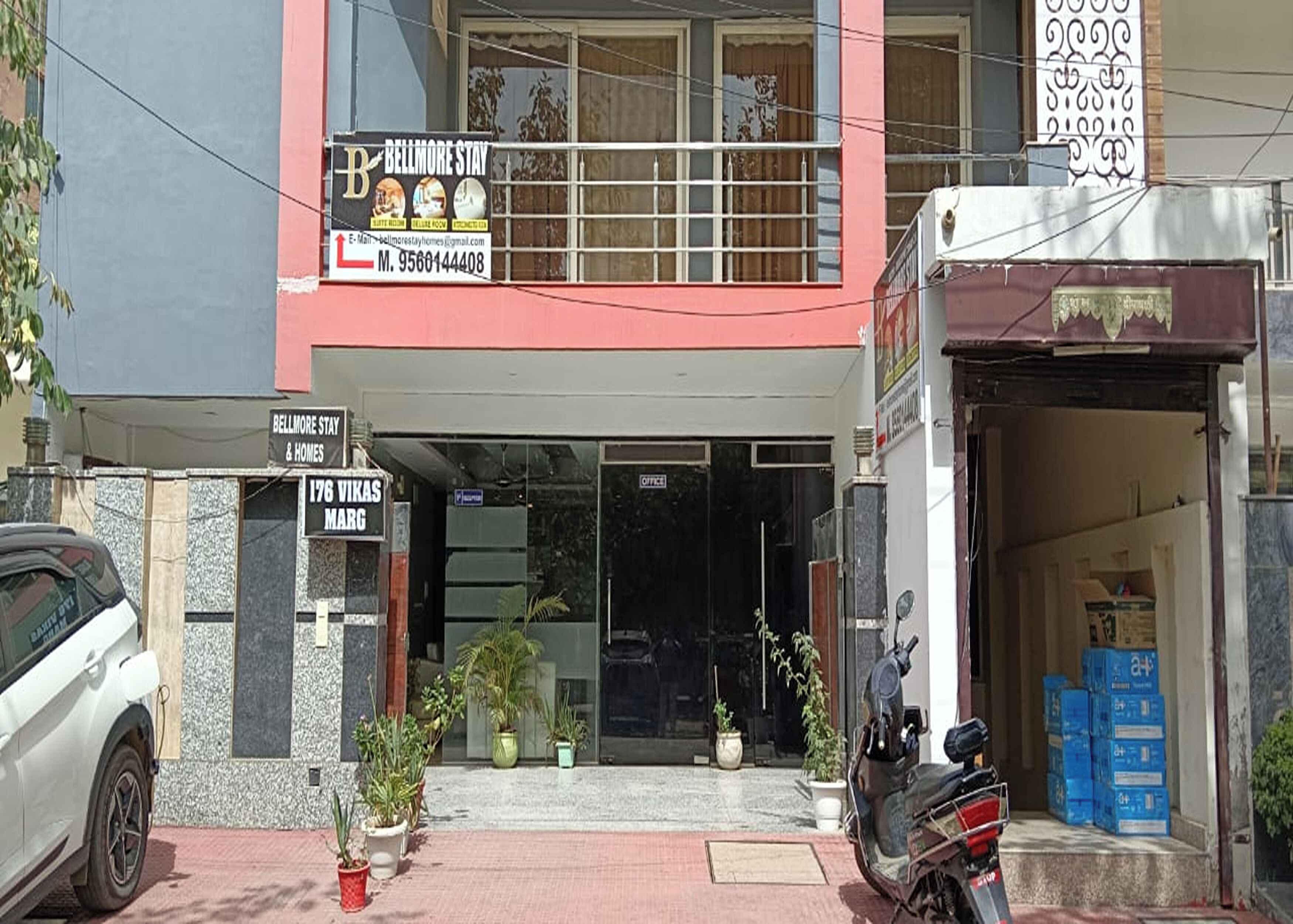Un edificio de dos pisos con un letrero que dice 'Bellmore Stay & Homes' y un cartel con la dirección '176 Vikas Marg'.
