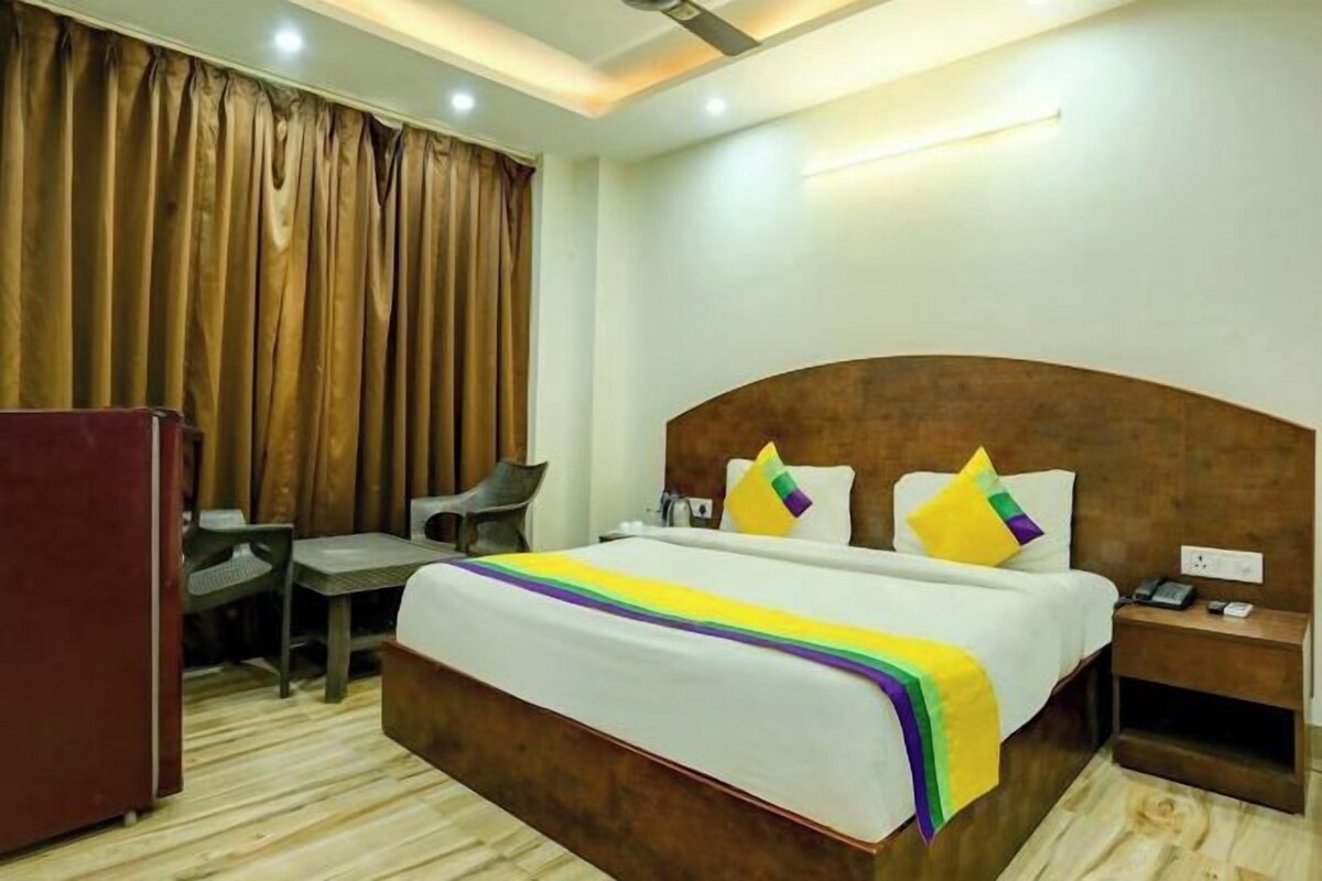A hotel room with a large bed, a desk, a chair, and a wardrobe.