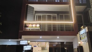 A multi-story hotel named Bellmore Stay with a modern design, featuring balconies and a well-lit facade. - Bellmore Stay & Homes (Gurugram)