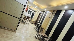 A spacious hotel lobby with a marble floor, modern furniture, and a striped wall design. - Bellmore Stay & Homes (Gurugram)