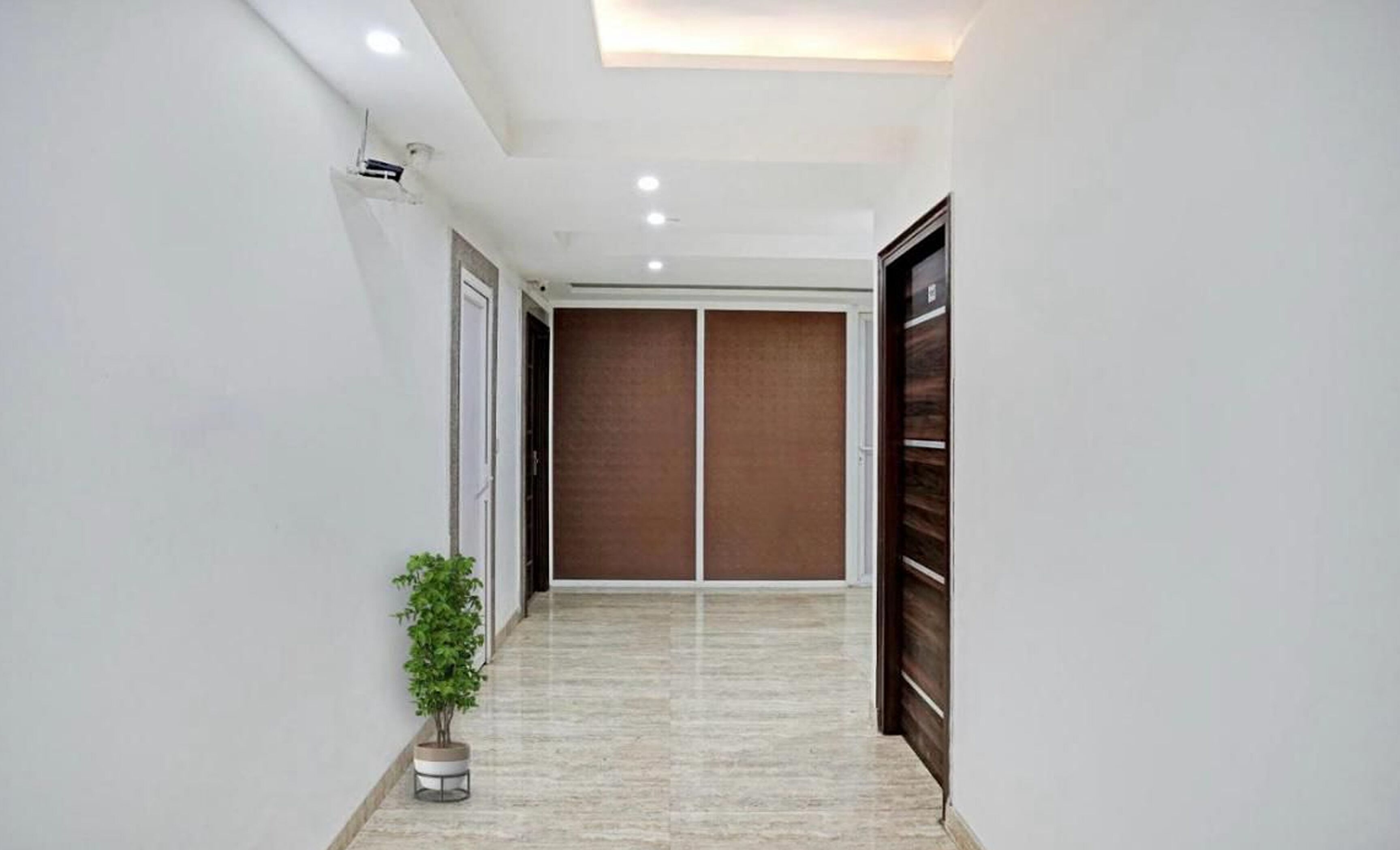 A hallway with a potted plant, a sliding door, and a wall-mounted air conditioning unit.