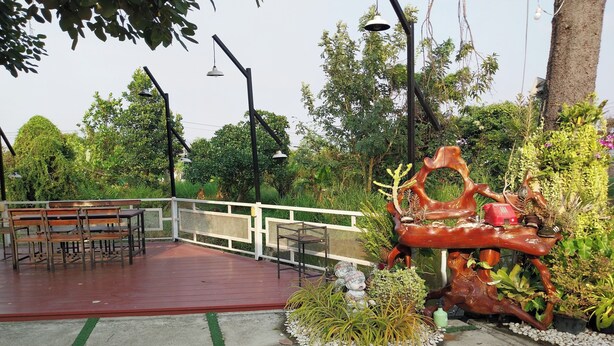An outdoor seating area with benches and tables, surrounded by greenery and decorative sculptures. - Review Resort (Sattahip)