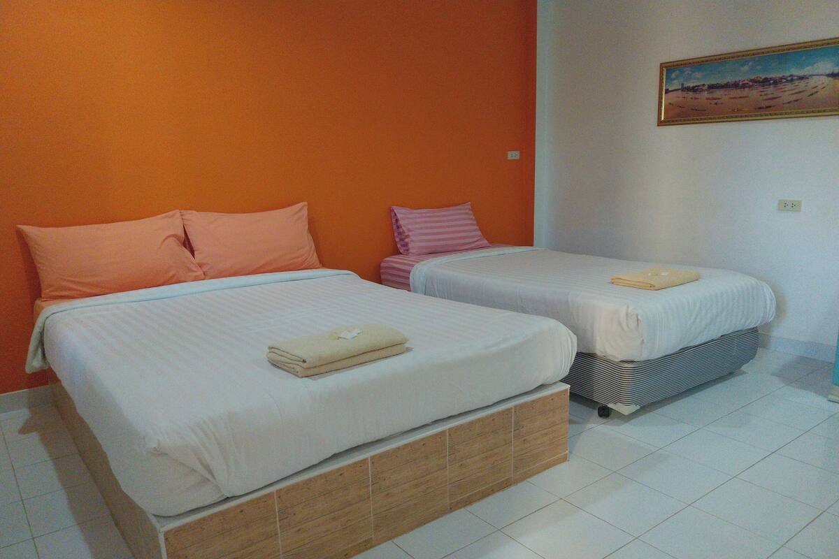 Quarto com duas camas, cada uma com travesseiro e toalha dobrada.