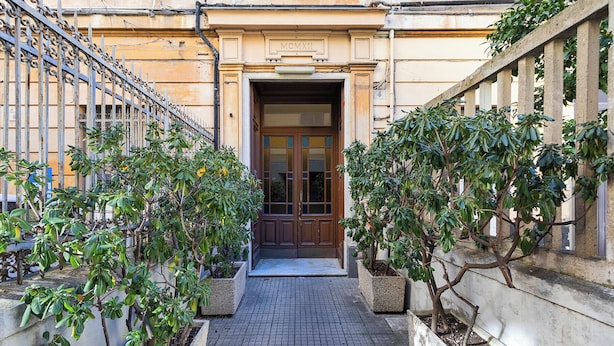 A narrow alleyway with a wooden door and a metal gate, flanked by potted plants. - Central & Cozy Apartment by Wonderful Italy (Genoa)