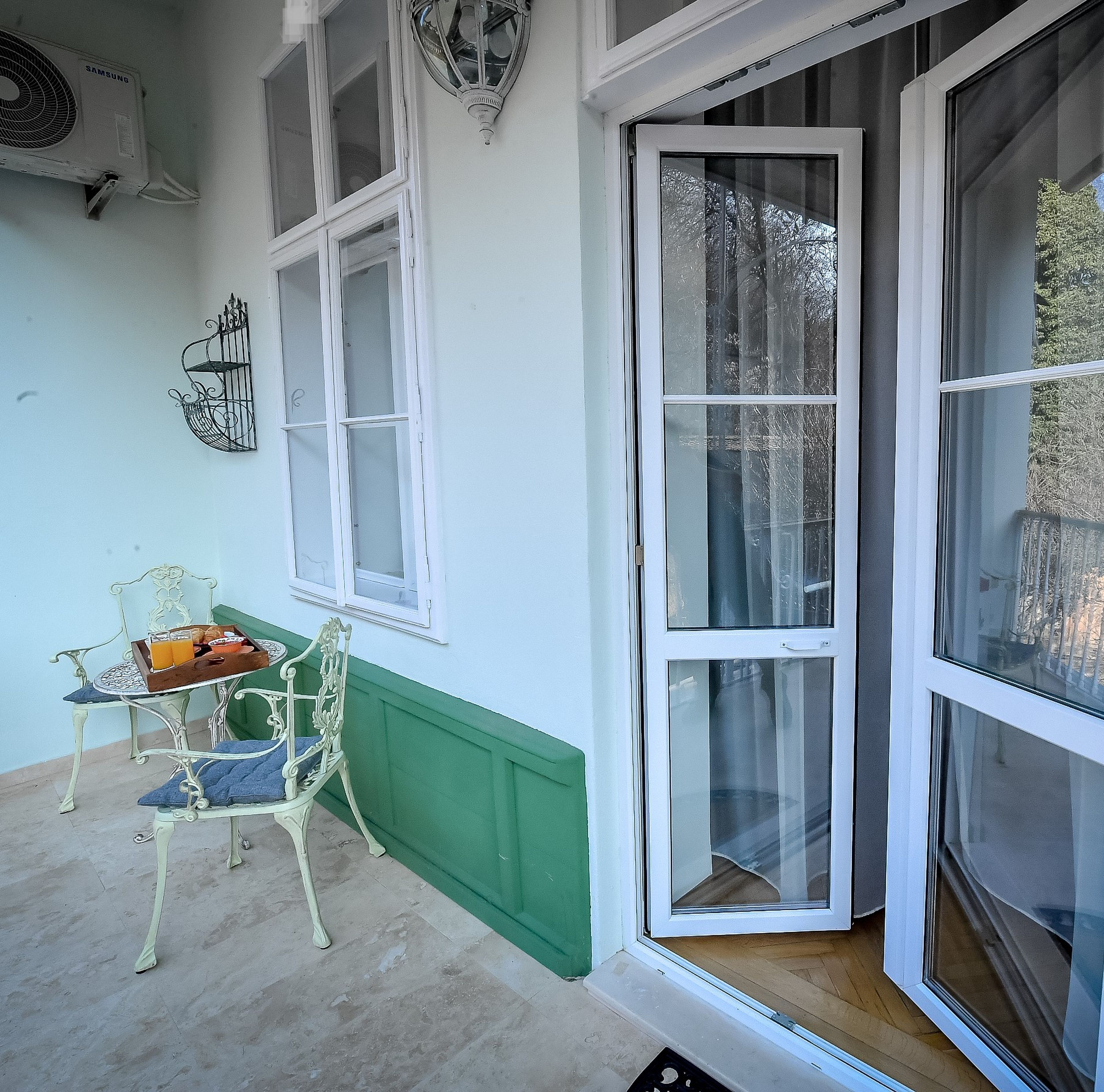 A conservatory with a table and chairs, a green wall, and a large sliding glass door.
