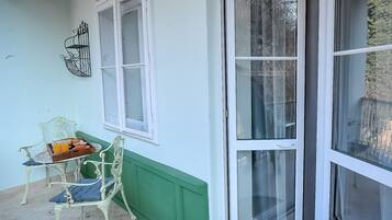 A conservatory with a table and chairs, a green wall, and a large sliding glass door.
