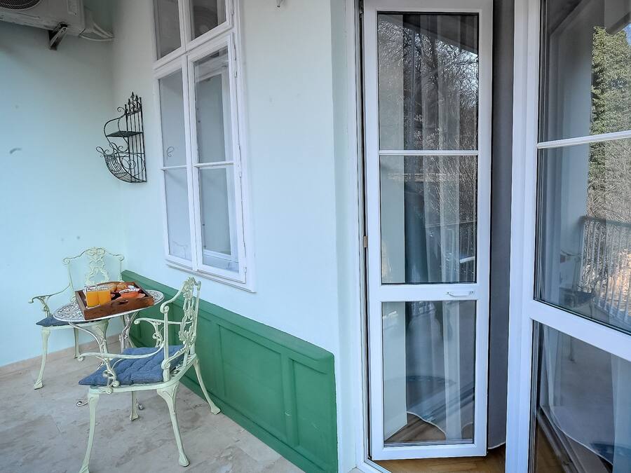 A conservatory with a table and chairs, a green wall, and a large sliding glass door.