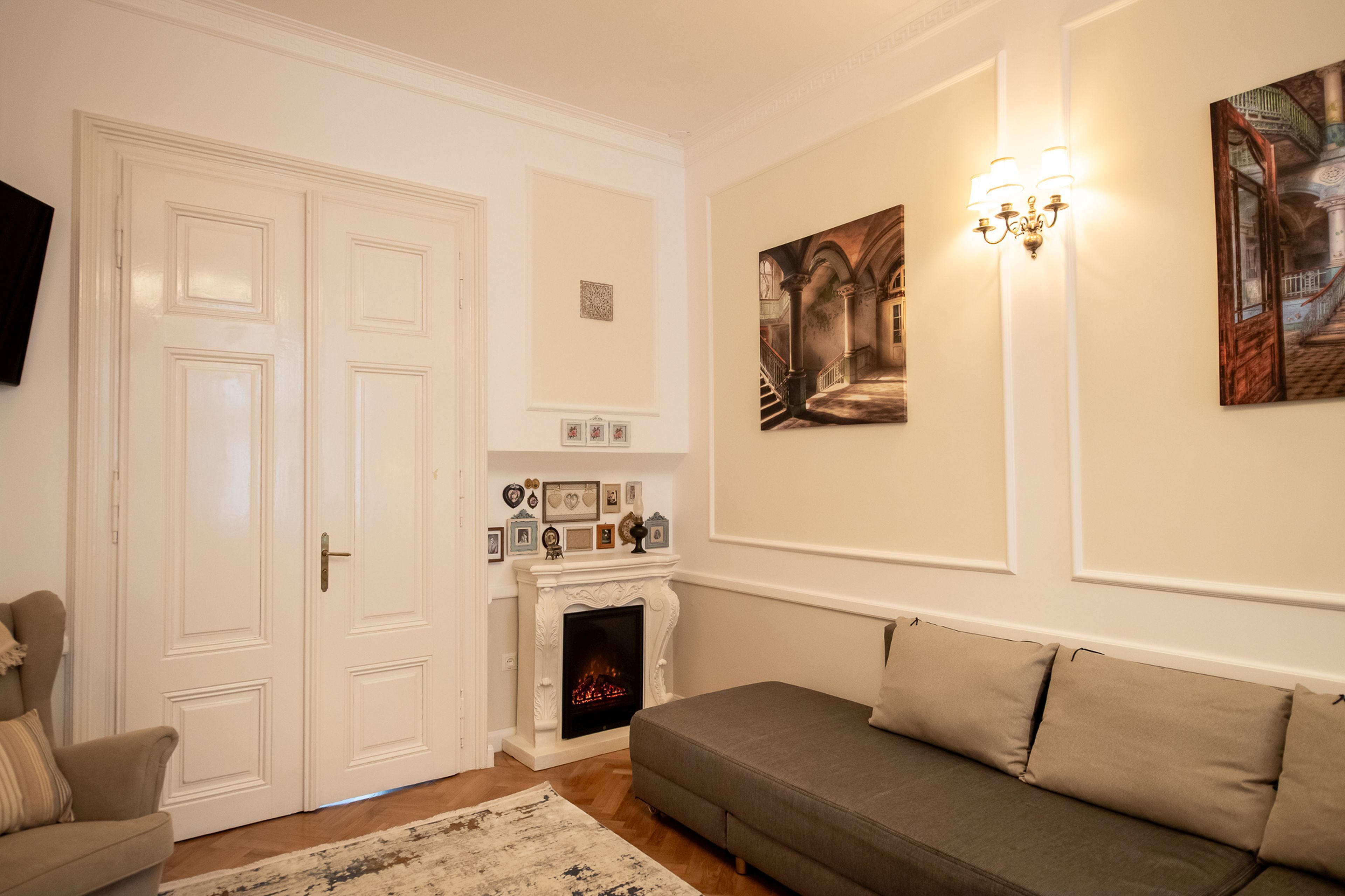 A living room with a fireplace, a sofa, a television, and wall-mounted artwork.