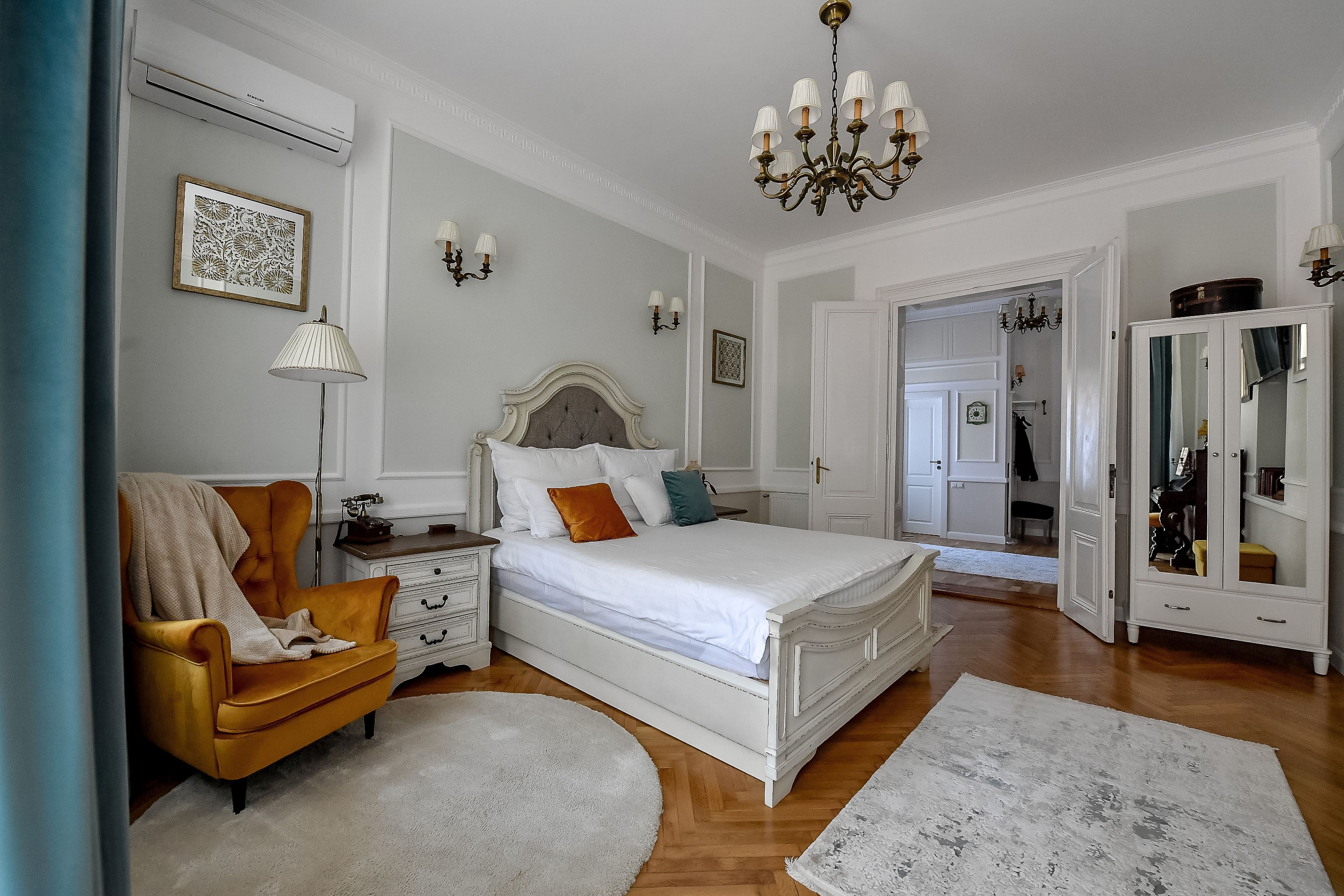 A bedroom with a bed, a chair, a dresser, and a wardrobe.