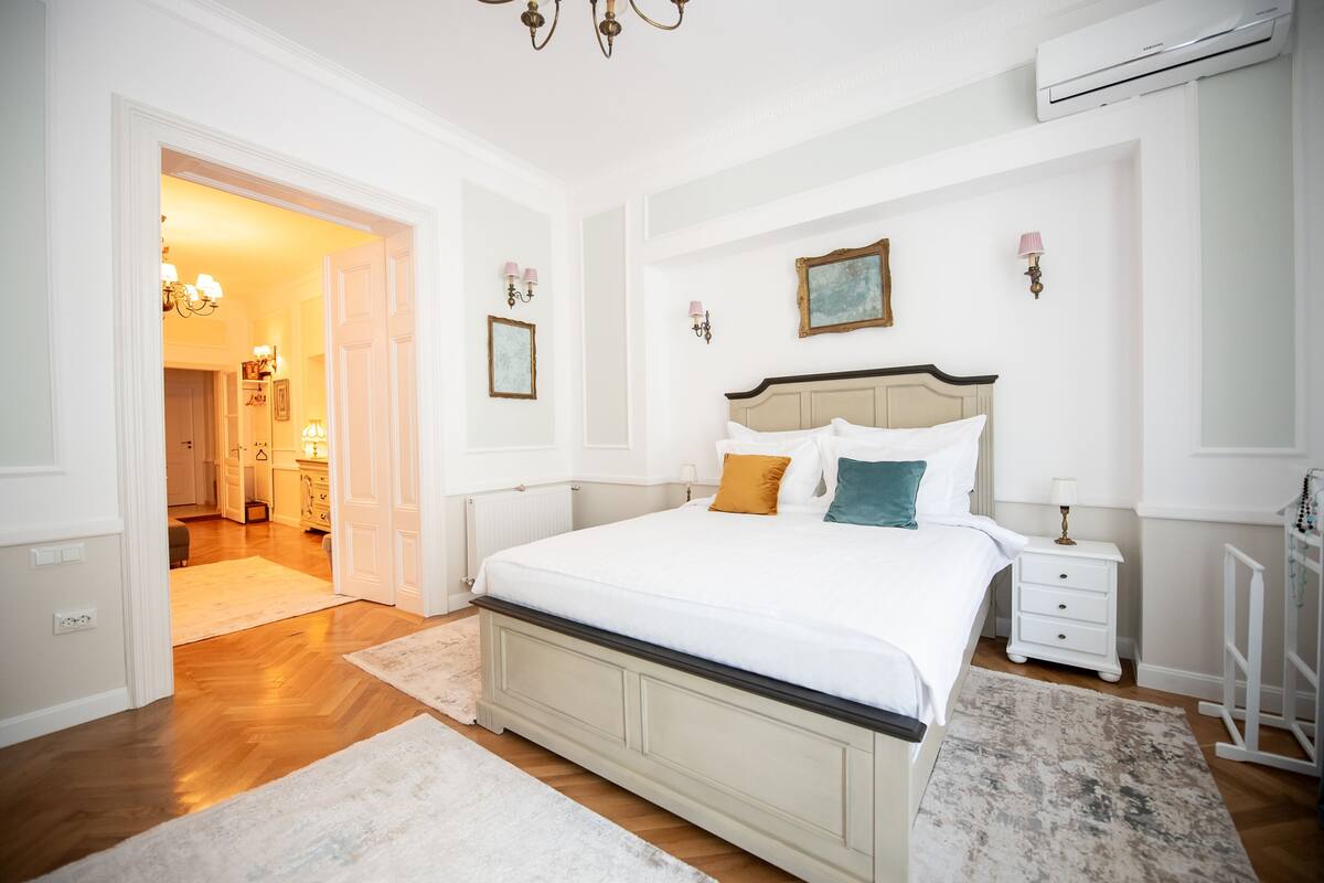 A bedroom with a large bed, a nightstand, a dresser, and an air conditioning unit.