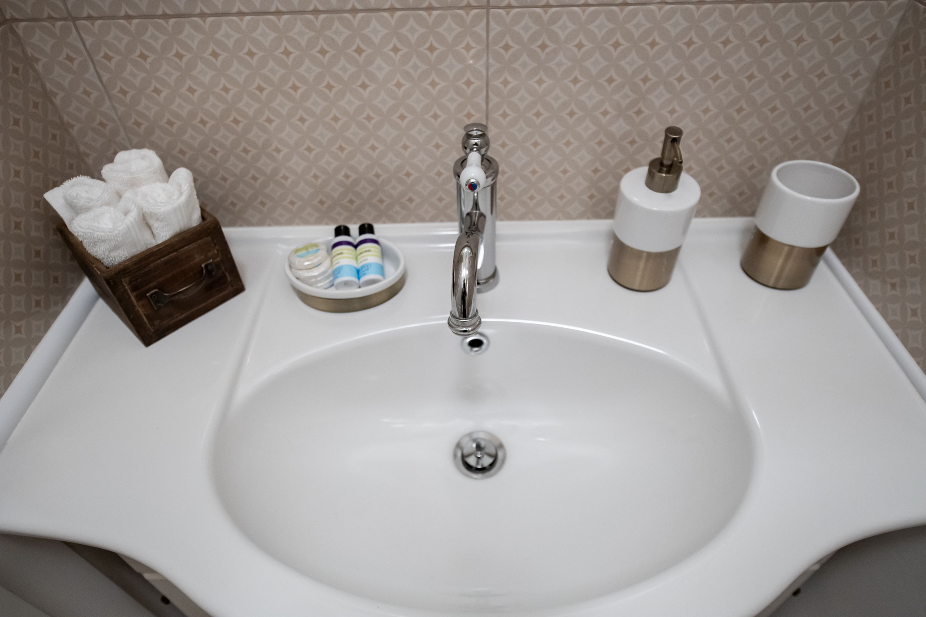 Un lavamanos con artículos de aseo y un portalápices para cepillos de dientes.