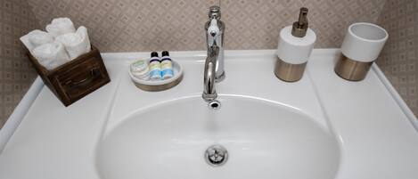 Un lavamanos con artículos de aseo y un portalápices para cepillos de dientes.