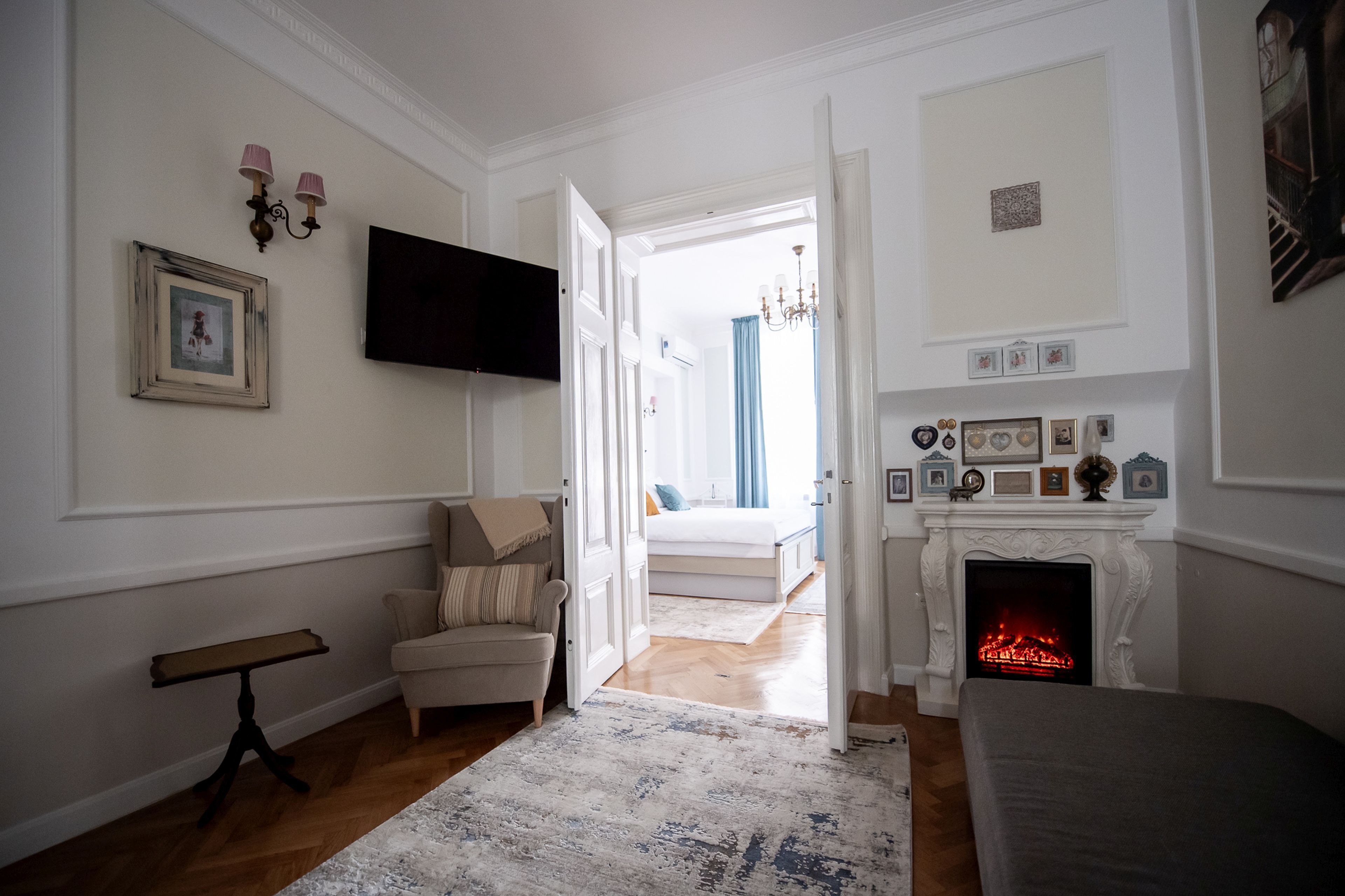 Una habitación con chimenea, una cama, un televisor y una puerta que da a otra habitación.