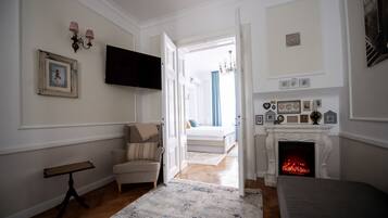 Una habitación con chimenea, una cama, un televisor y una puerta que da a otra habitación.