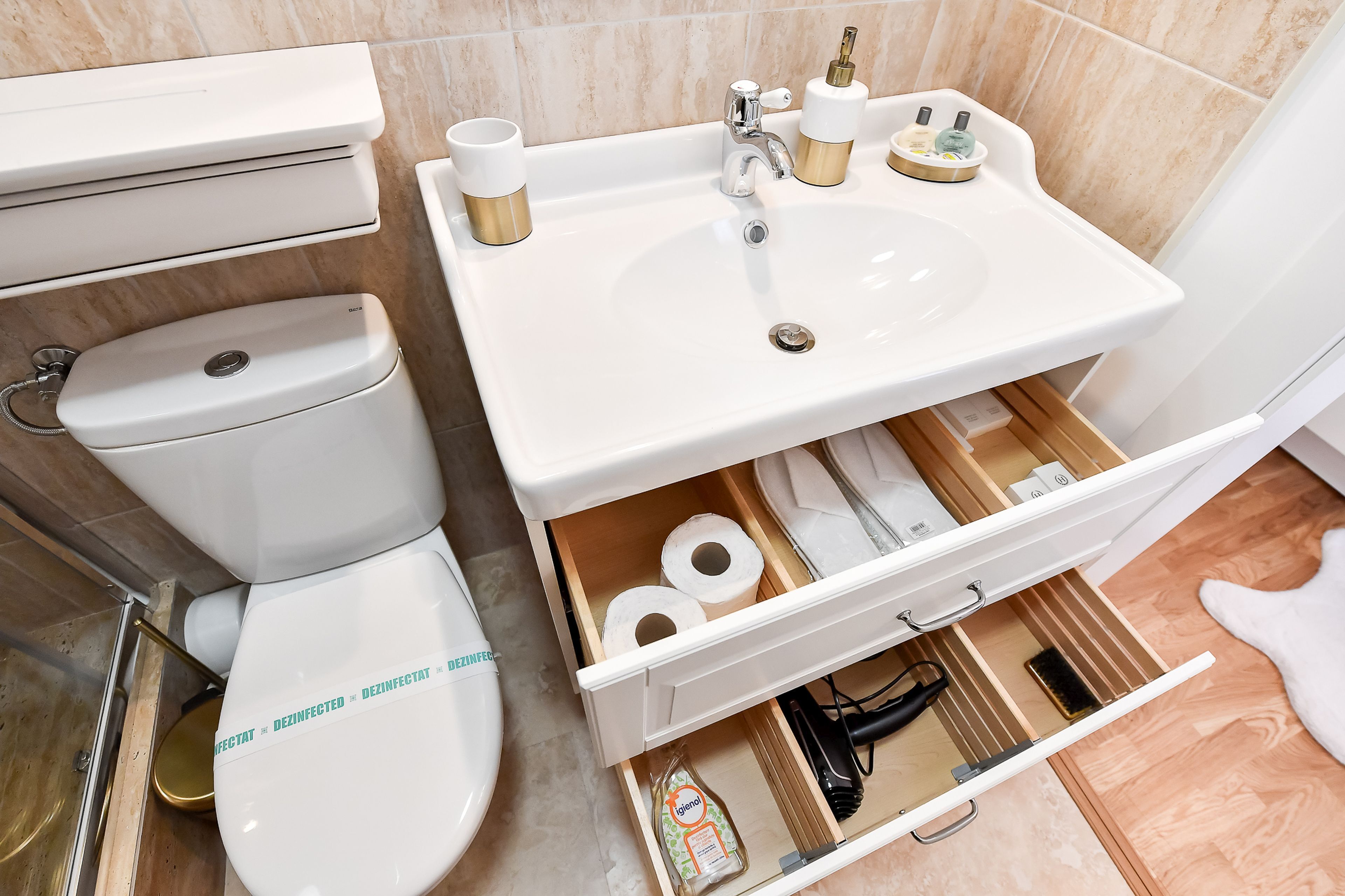 A bathroom with a toilet, sink, and storage drawers.
