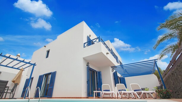 A modern building with a pool, blue shutters, and white walls. - Casa Maria del Mar 2 Minutes From Supermarkets & 10 Minutes From Marina Rubicón (Playa Blanca)