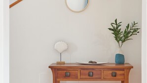 A wooden console table with a white shell lamp, a blue vase with green plants, and two round mirrors on the wall above. - Casa Maria del Mar 2 Minutes From Supermarkets & 10 Minutes From Marina Rubicón (Playa Blanca)