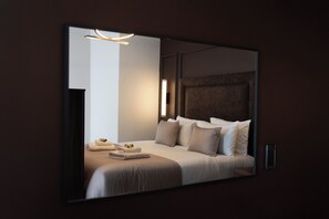 A modern hotel room with a large bed, a bedside table, a wall-mounted light, and a mirror. - Cae Mor Hotel (Llandudno)