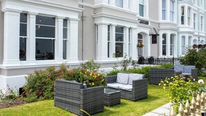 A hotel exterior with a garden patio area featuring wicker furniture. - Cae Mor Hotel (Llandudno)