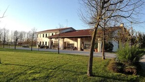 A two-story building with a tiled roof, a covered porch, and a well-maintained lawn.