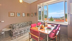 A dining area with a table set for four, a sofa, and a window with a view. - Pinehome & Garden - Total Relax (Borghetto Santo Spirito)