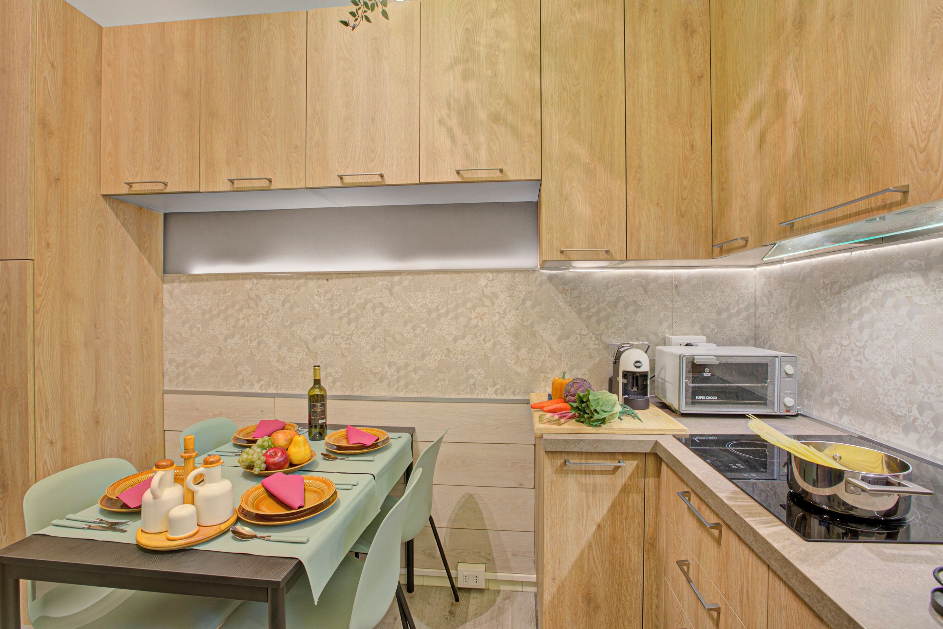 Une cuisine moderne avec des meubles en bois, une table à manger pour quatre personnes, un grille-pain et une cuisinière.