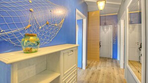 A hallway with a blue wall, a decorative net, and a wooden door. - Pinehome & Garden - Total Relax (Borghetto Santo Spirito)