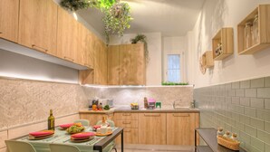 A modern kitchen with wooden cabinets, a dining table set with pink placemats, and a hanging plant. - Pinehome & Garden - Total Relax (Borghetto Santo Spirito)