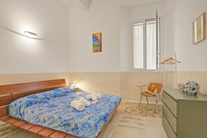 A bedroom with a bed, a chair, a dresser, a vase, and a painting on the wall. - Beach & Relax - Private Parking and Veranda (Alassio)