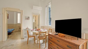 A modern living room with a flat-screen TV, wooden furniture, and a dining area with a table and chairs.