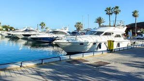 A marina with several boats docked, a wooden walkway, and palm trees in the background. - Penthouse @ Las Mimosas Cabopino (Marbella)