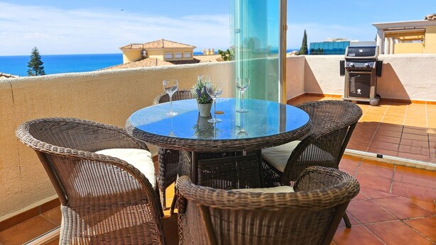 A balcony with wicker furniture, a glass table, and a grill. - Penthouse @ Las Mimosas Cabopino (Marbella)