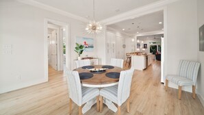 Een moderne keuken met witte kasten, een houten eettafel en een hanglamp.