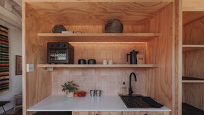 Une cuisine compacte équipée d’un four encastré, d’un évier et d’une machine à café posée sur le plan de travail.