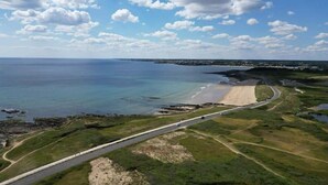 Vista aérea de una zona costera con playa, carretera y cielo despejado.