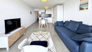 Una sala de estar moderna con televisión, sofá y comedor.