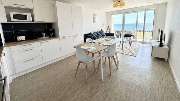 Una cocina moderna con armarios blancos, un microondas y una zona de comedor con mesa y sillas.