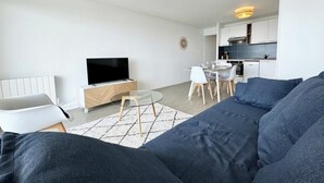 Una sala de estar moderna con sofá, televisión y comedor.