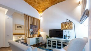 A modern living room with a sofa, armchair, TV, and decorative items. - Casa da Tammy Olhão Portugal (Olhão)